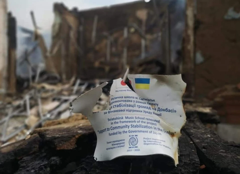 залишок сертифікату про відновлення школи Святогірська на Донеччині на фоні її руїн