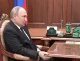 Володимир Путін тримається за стіл під час зустрічі в Кремлі