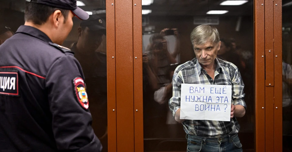 Олексій Горінов тримає табличку з написом "Вам ще потрібна ця війна?"