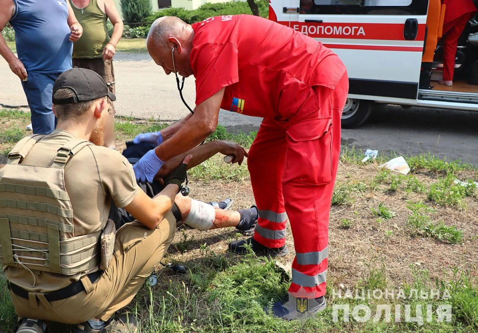 На фото лікар та поліцейський допомагають пораненій людині