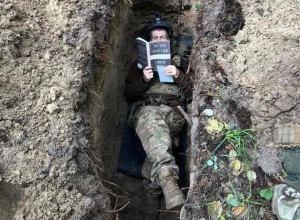 Воїн ЗСУ в окопі читає книгу Тімоті Снайдера