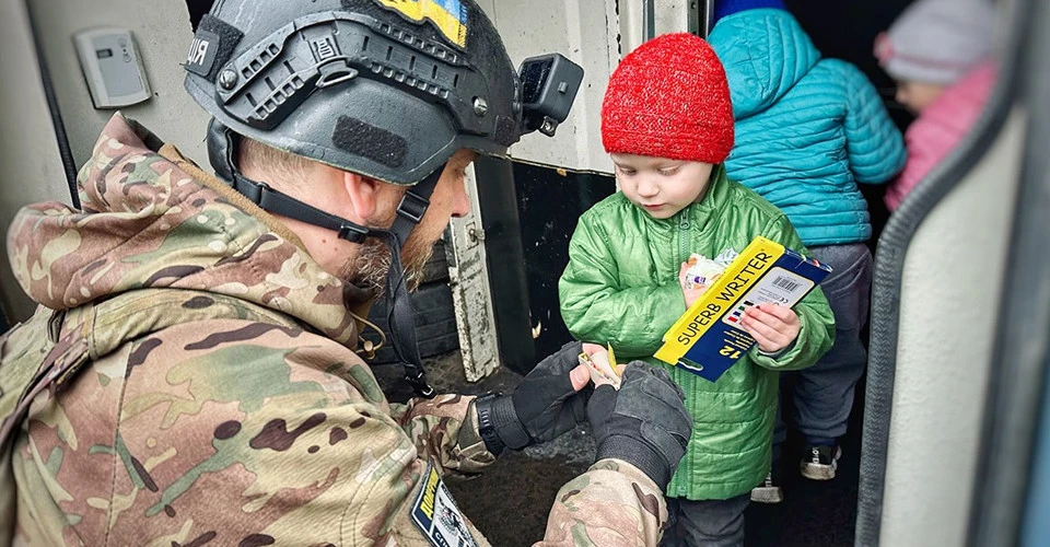 Поліцейський вивозить мирних мешканців із зони активних бойових дій