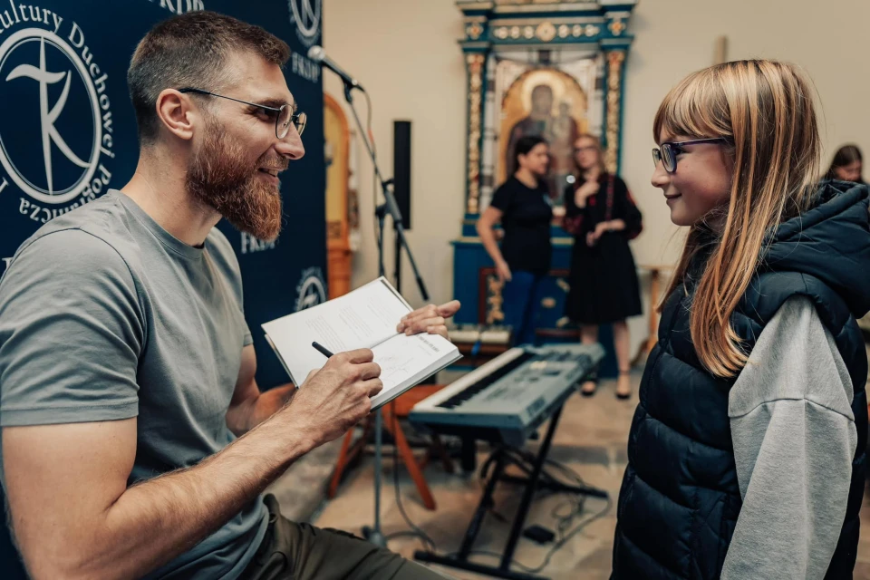 на фото Павло Вишебаба підписує книгу для дівчинки