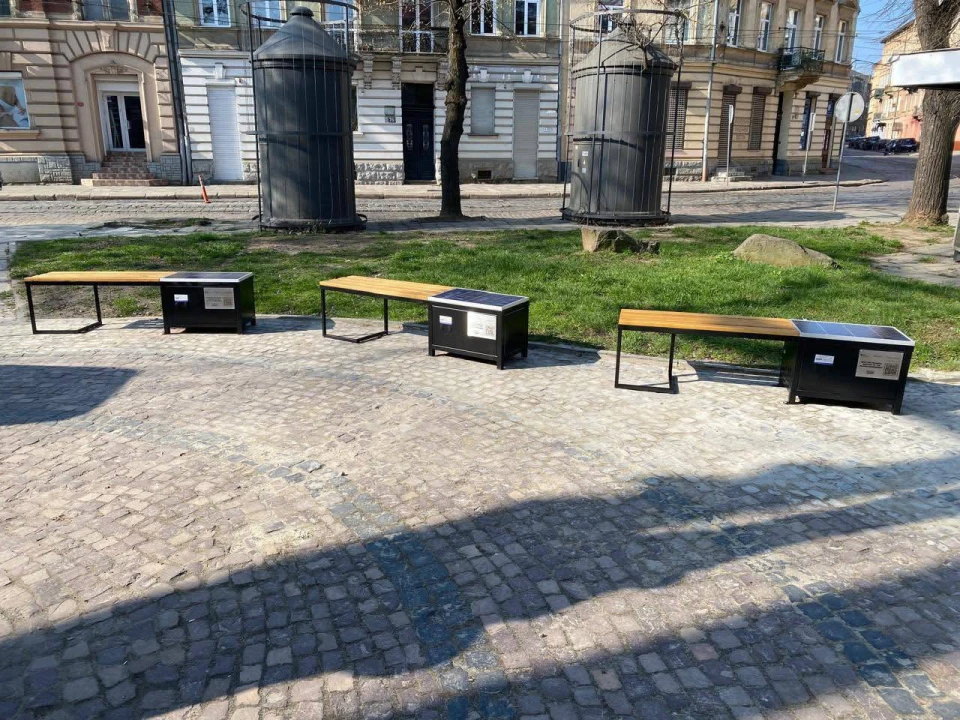 Лавки з сонячними панелями з підзарядки пристроїв поручз з Бернардинським собором