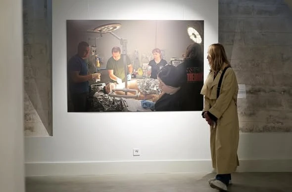 На фото: відвідувачка розглядає документальний знімок з операційної на фотовиставці "Хартія: Спека. 11 поглядів на війну" у підземеллі Ратуші у Львові, 4 квітня 2026 року