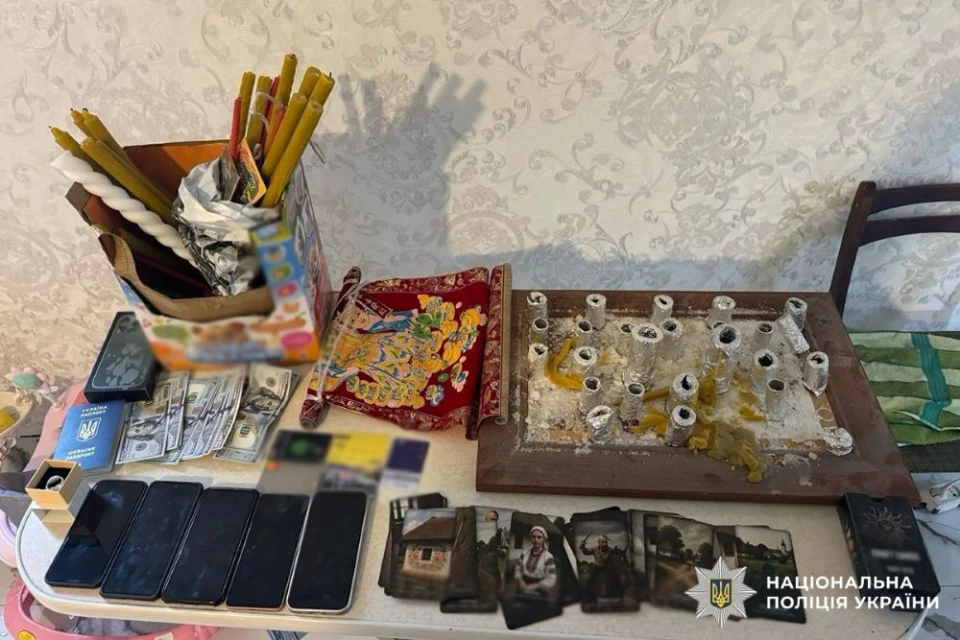 Речі, виявлені при обшуку "ясновидиці": свічки, колода карт таро, картина, телефони, готівка у доларах, банківські картки, паспорт