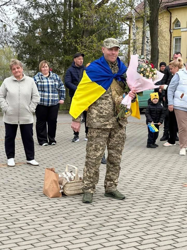 На фото: воїн Павло Юркевич із прапором України та квітами під час зустрічі у Добротвірській громаді на Львівщині